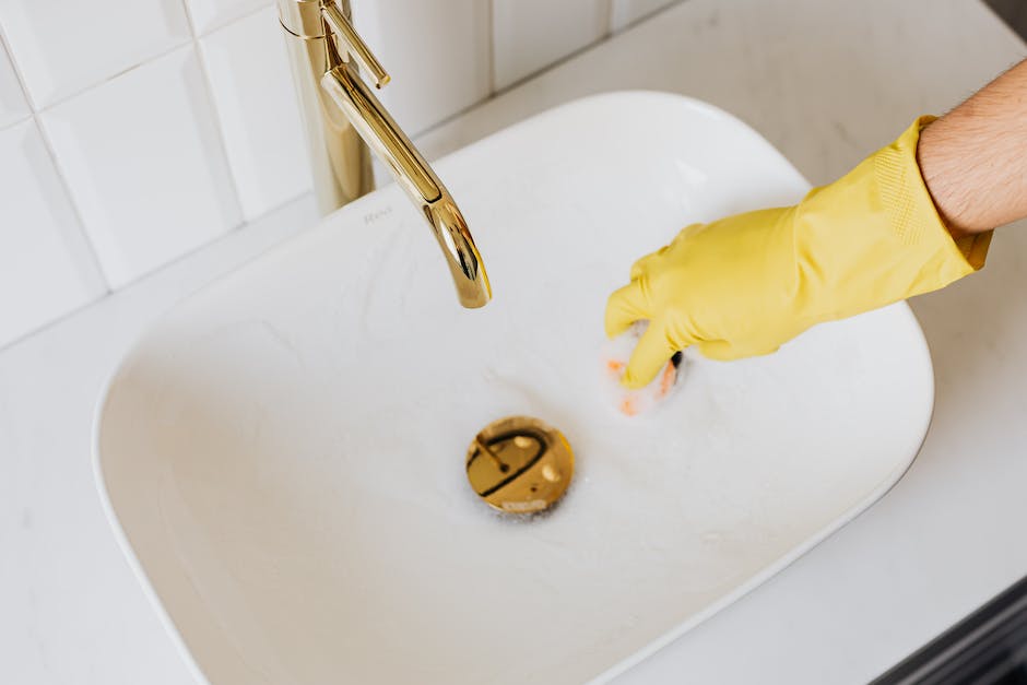 A person scrubbing a white sink with a sponge, removing stains.